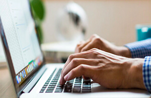 Hands typing on a laptop