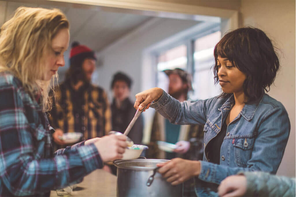 Woman serving soup to a homeless person